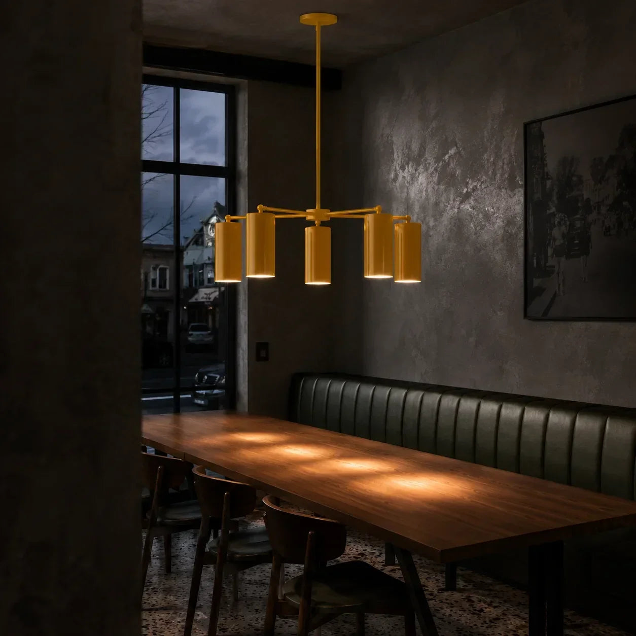 Yellow modern chandelier with multiple cylindrical shades above a dining table