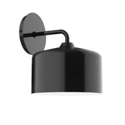 Black wall sconce with round backplate, curved arm, and cylindrical shade