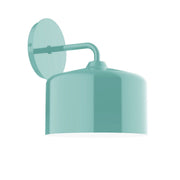 Sea green wall sconce with round backplate, curved arm, and dome shade.