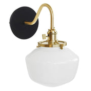 Black wall sconce with brushed brass curved arm and frosted glass dome shade