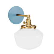 Light blue wall sconce with brushed brass mount and white glass dome shade.